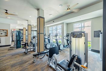 A gym with a variety of equipment including treadmills, weights, and exercise machines.